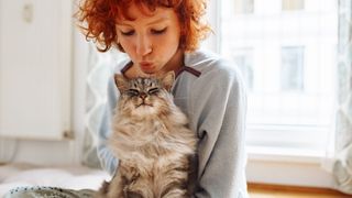 Red haired woman cuddling cat