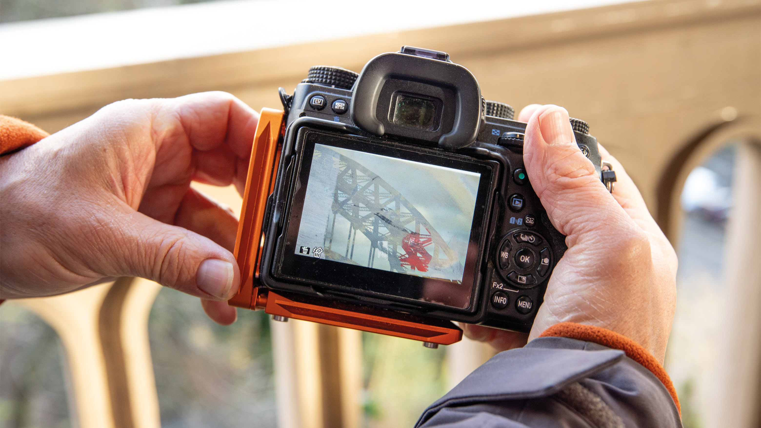 A man holding a camera outdoors showing the multi exposure menu on-screen