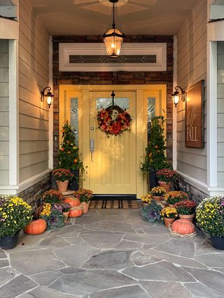 fall front door decor, yellow door with autumn wreath and pumpkins
