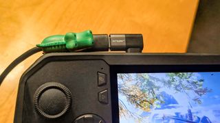 JSAUX right angle USB-C adapter connected to an ROG Ally X with a green alligator cable protector on the charging cable. 