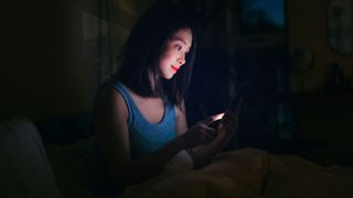 Woman listening to brown noise sleep app in bed at night