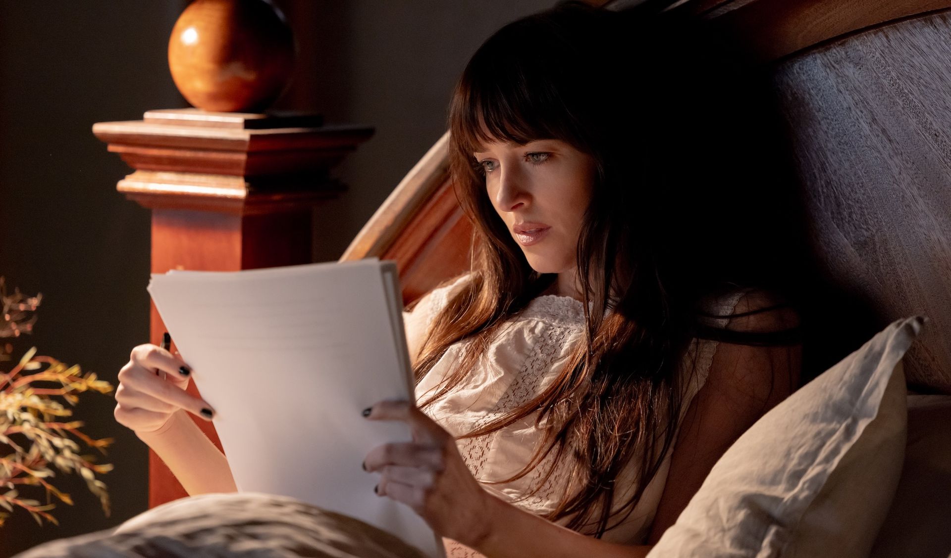 Dakota Johnson reading in bed in Verity
