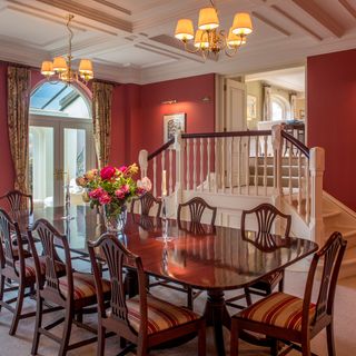 dining room with red wall and wooden dining table and chairs