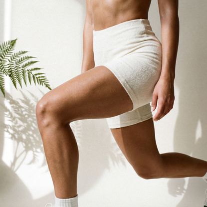 woman wearing white exercise shorts doing a lunge