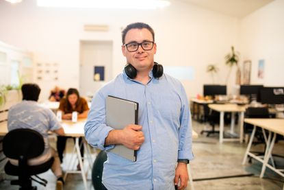 A man with Down's Syndrome standing in a co-working space with his laptop