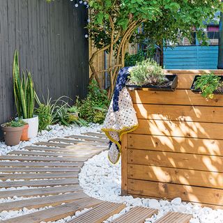 decking path with white pebbles and grey fence