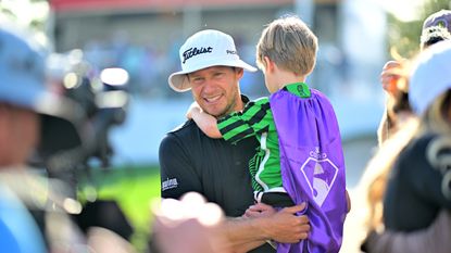 Peter Malnati holds his son Hatcher in his arms while looking emotional after the Valspar Championship