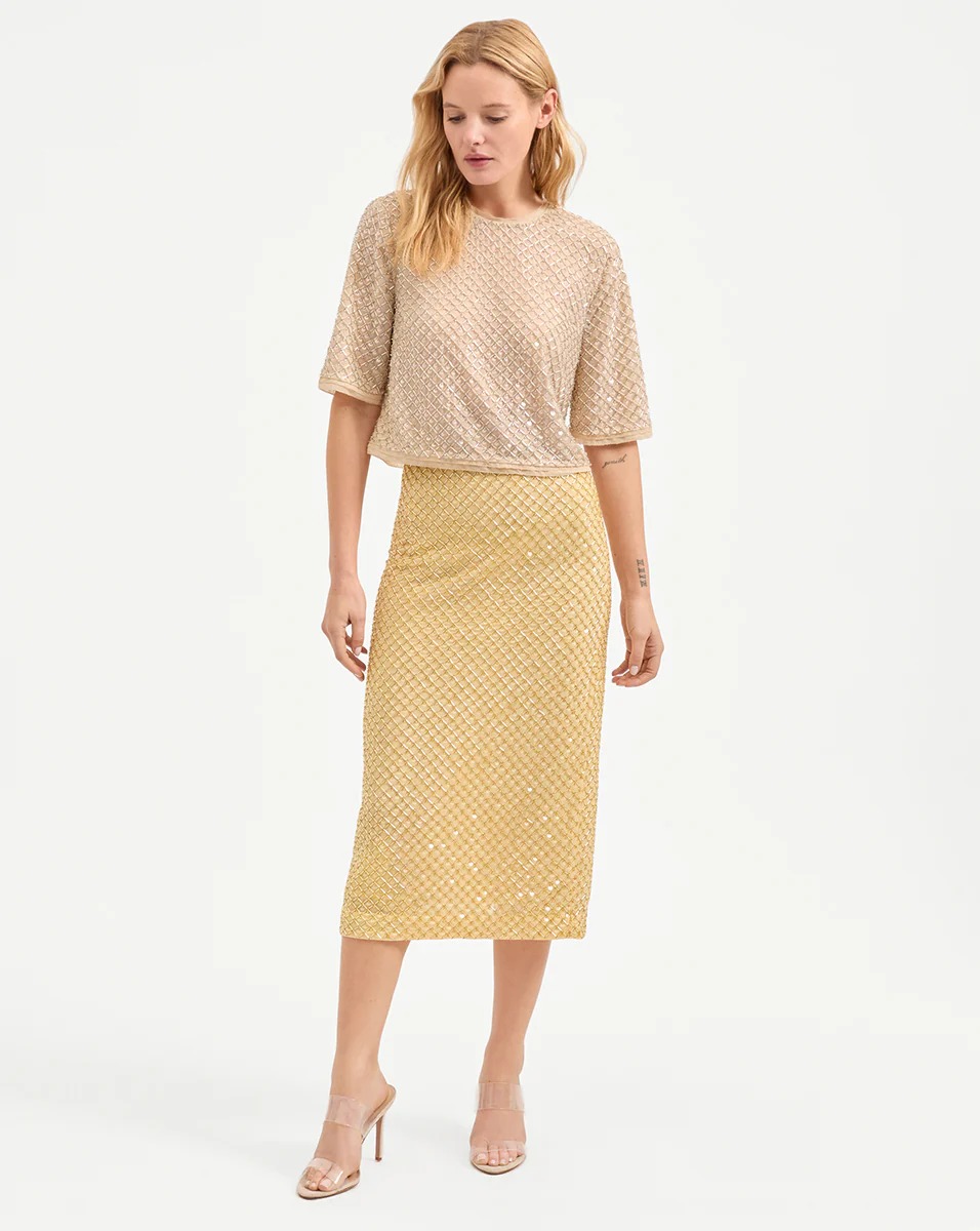 A model wearing a yellow beaded midi skirt.