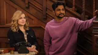 Pictured (L-R): Rose McIver as Samantha and Utkarsh Ambudkar as Jay both standing in the lobby of their in. Sam is behind the desk and Jay has his arm resting on the staircase.