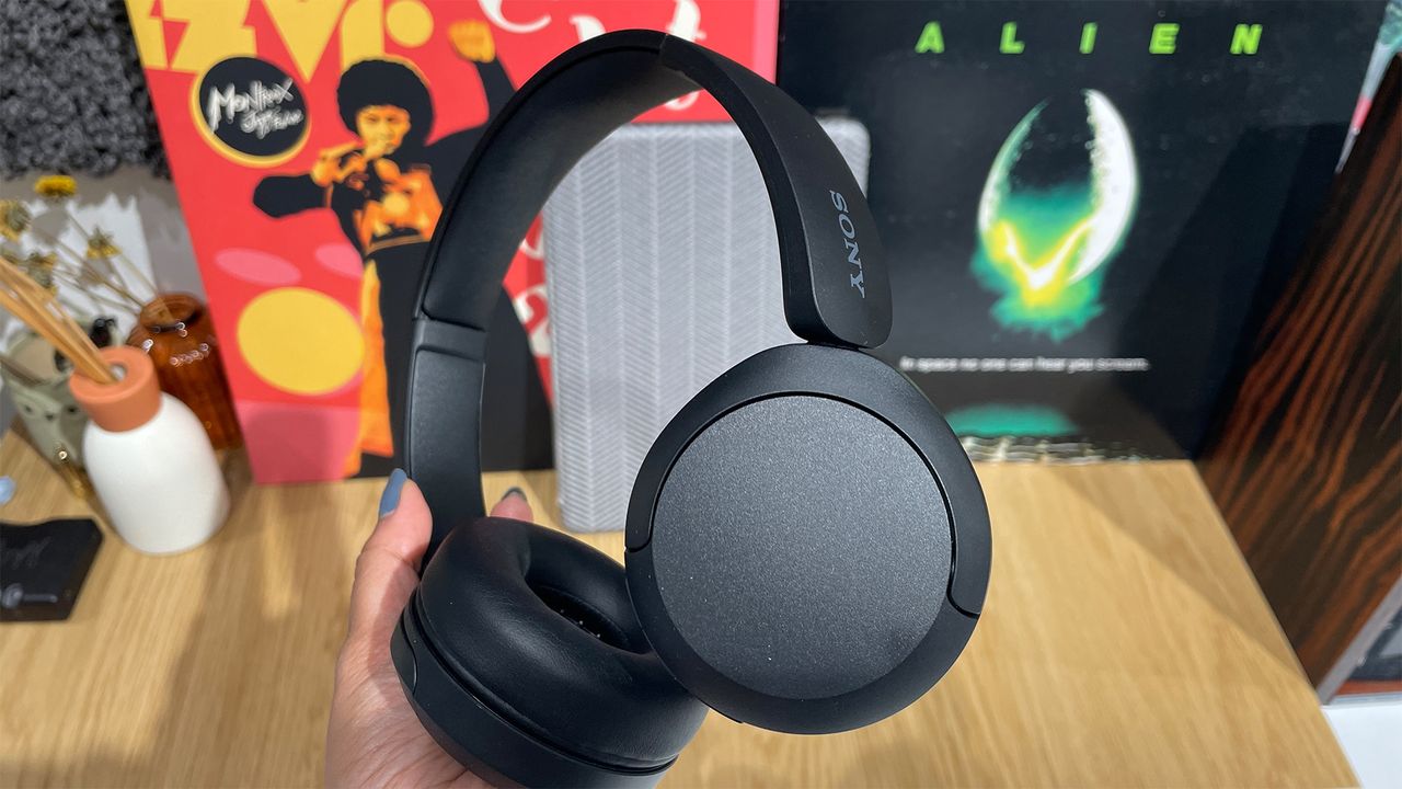 A hand holding a black pair of Sony WH-CH520 over-ear headphones by one of the earcups.