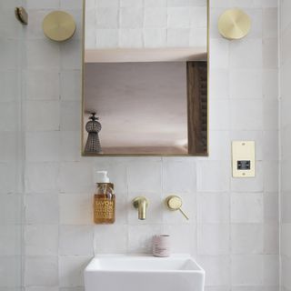 White bathroom with gold hardware and mirror