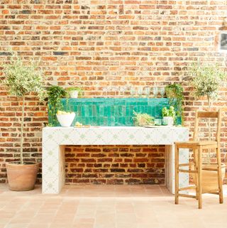 tiled outdoor kitchen against a brick wall