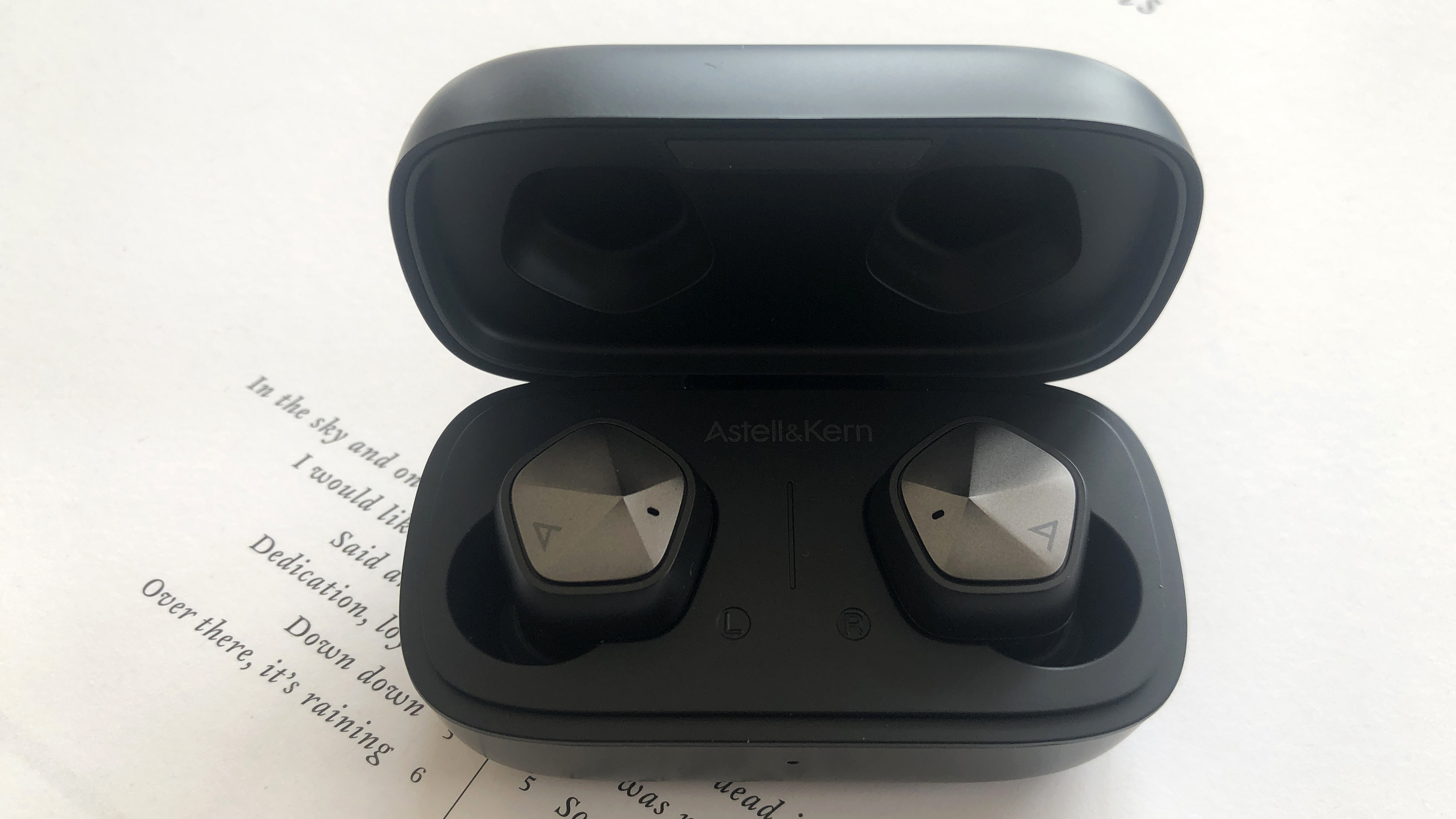 Astell & Kern UW1000 earbuds on surface showing song lyrics