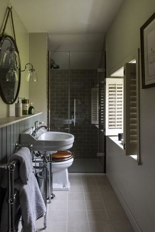 en suite bathroom with tiled flooring and grey tiled walls