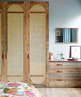 bedroom with cupboard with rattan doors, wooden drawers and colorful bedspread
