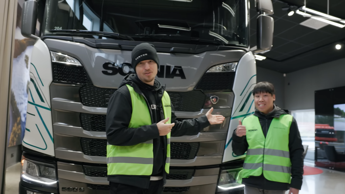 Two men standing in front of a big truck and smiling.