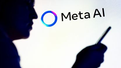 Meta AI logo and branding pictured on a wall with silhouette of man holding up smartphone in foreground.