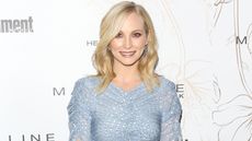 Candice King in a blue dress in front of a white background
