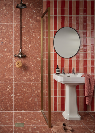 a brown bathroom with brown terazzo tiles and red and pink stripe tiles on the wall