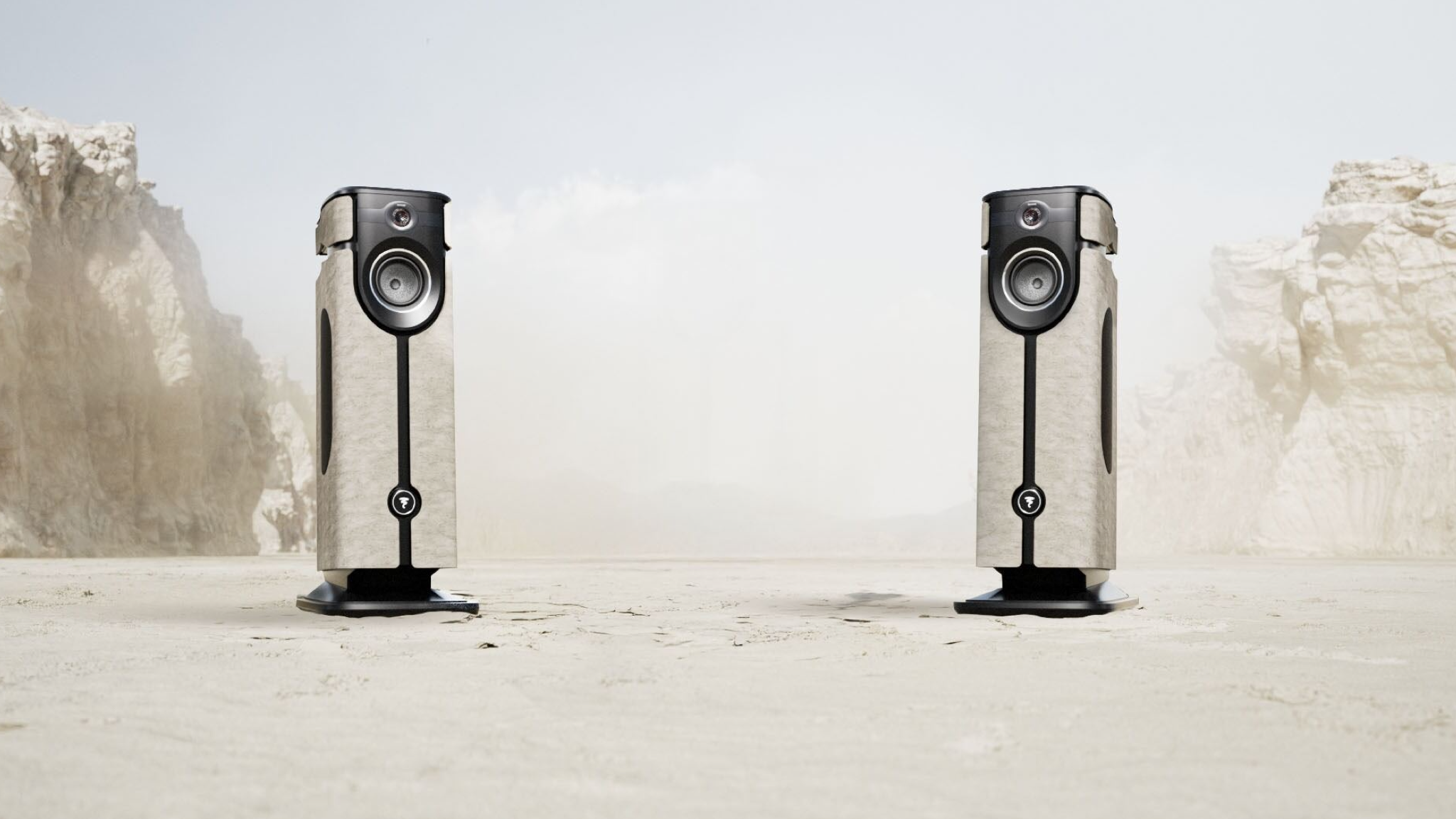 Lifestyle image of the Focal Diva Mezza Utopia showing two speakers on sandy ground with big rocky outcrops in the background