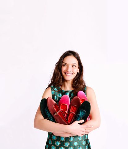 A woman holding several Birdies ballet flats in her arms