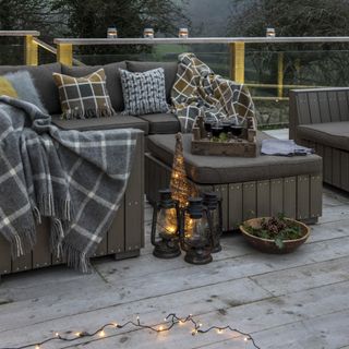 Wooden deck with outdoor seating and table, cushions, blankets and lanterns