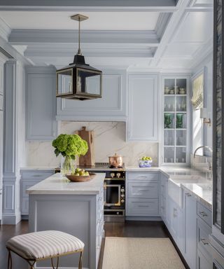 light blue color-drenched kitchen with kitchen island, vase of flowers and brass accents