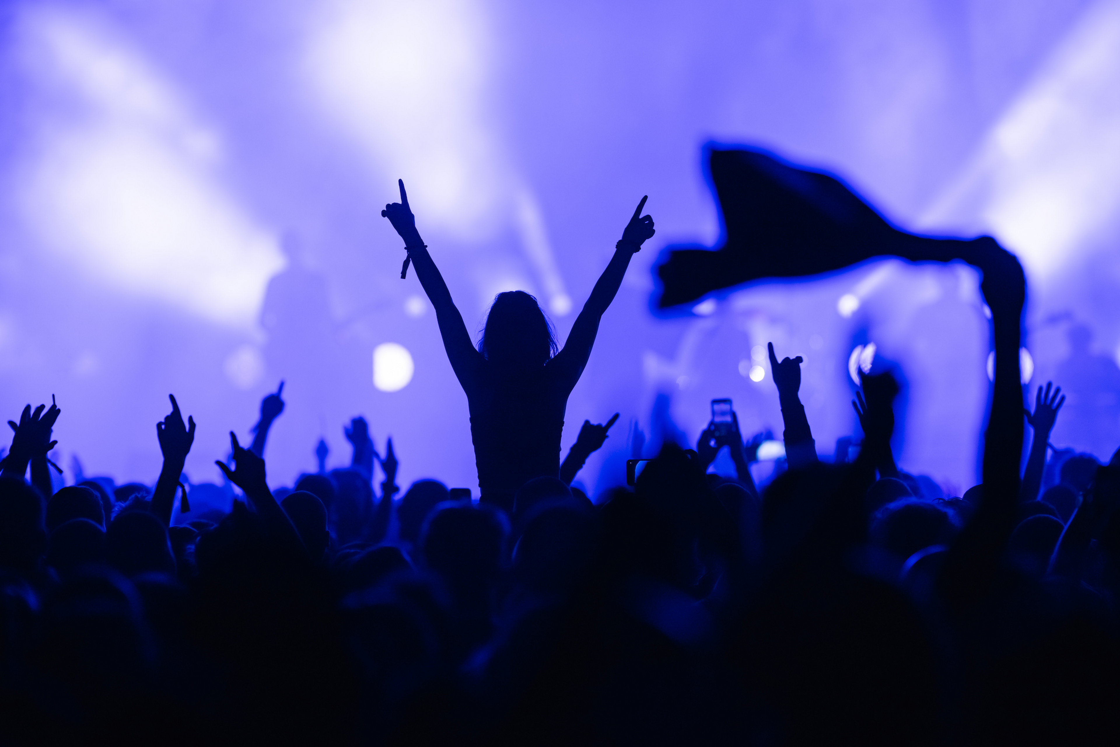 A crowd are in front of a blue lit stage 