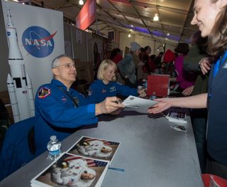 NASA Astronaut Lee Morin, a veteran of space shuttle mission STS-110, signs autographs at the NASA booth set up on the National Mall as part of the National Day of Service, Saturday, January 19, 2013.