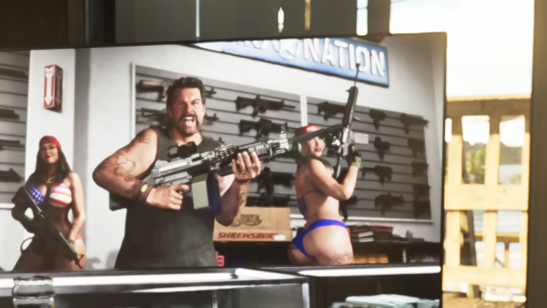 GTA 6 weapons: A gun store owner on TV with a rack of SMGs on the back wall.