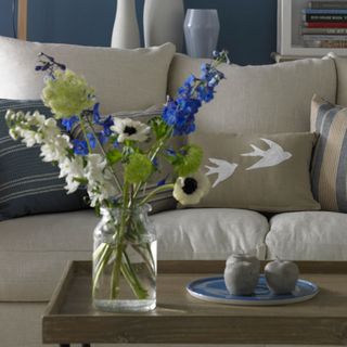 flowers in glass vase on coffee table in front of sofa