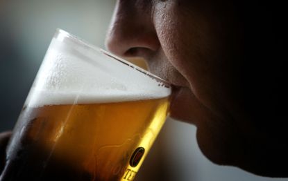 A man drinks a glass of beer.