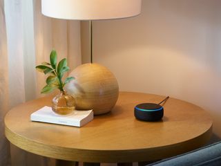 An Amazon Echo Dot on a table surrounded by neutral decor