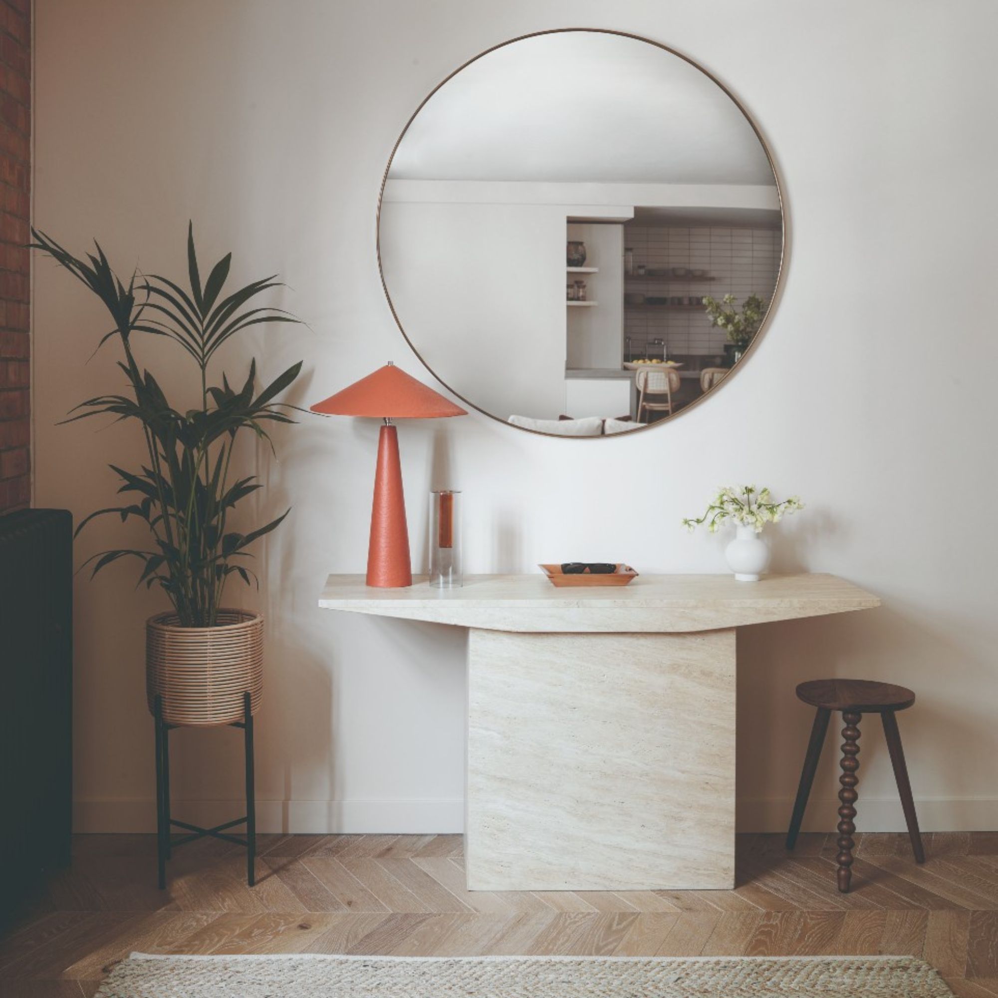 Entrance hall with wooden floor, neutral walls and large marble sideboard. Plant to add greenery, wooden side table and large round mirror