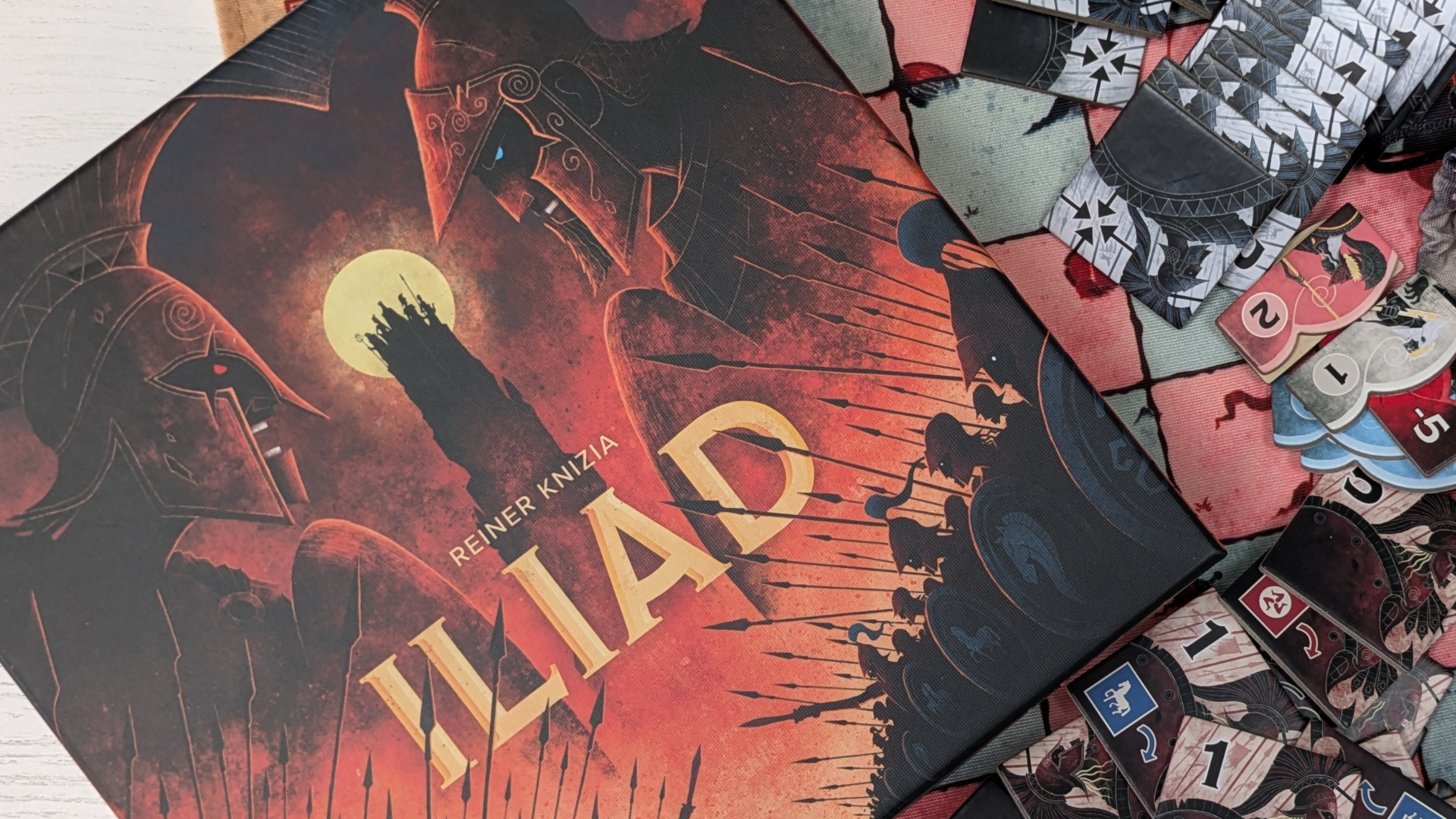 Iliad box, tokens, and components laid out on a white surface