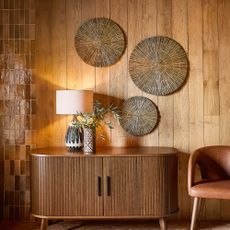 wood clad walls with wooden console table and rattan wall art and leather chair