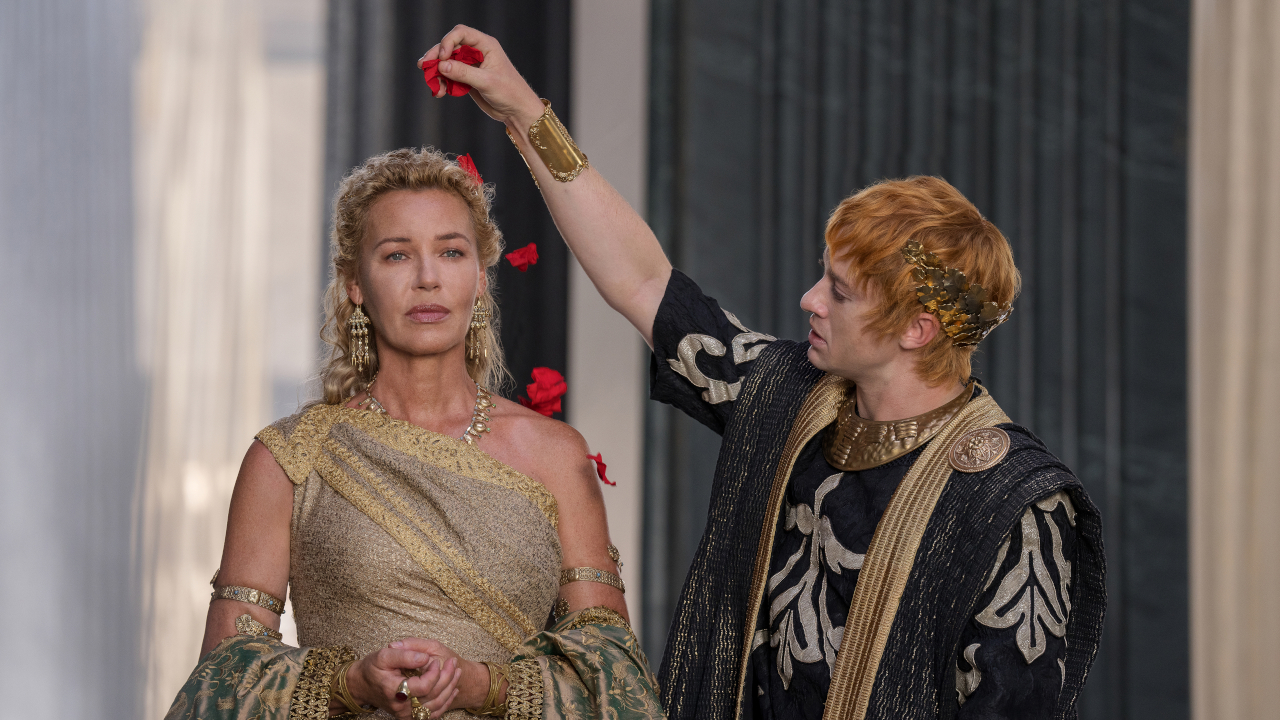 Connie Nielsen stands regally with tears in her eyes while Joseph Quinn showers her with rose pedals in Gladiator II.