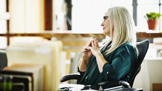 Best ergonomic office chairs: An older woman with grey-blonde hair relaxes in a supportive home office chair