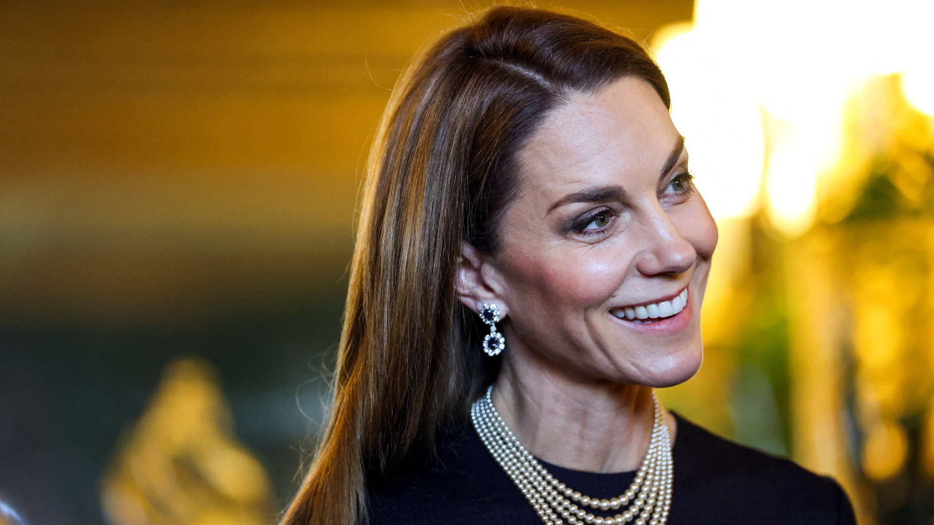 Princess Kate wearing a pearl necklace and sapphire earrings and smiling