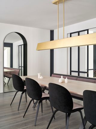 Dining room with long table and chairs and gold hanging light