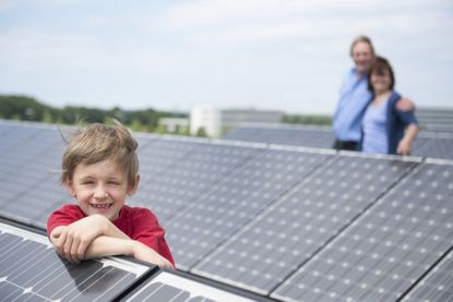 A solar farm with a child in foreground and parents in the background