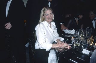 A photo of Carolyn Bessette-Kennedy sporting a white shirt and a black skirt at a benefit in 1999.