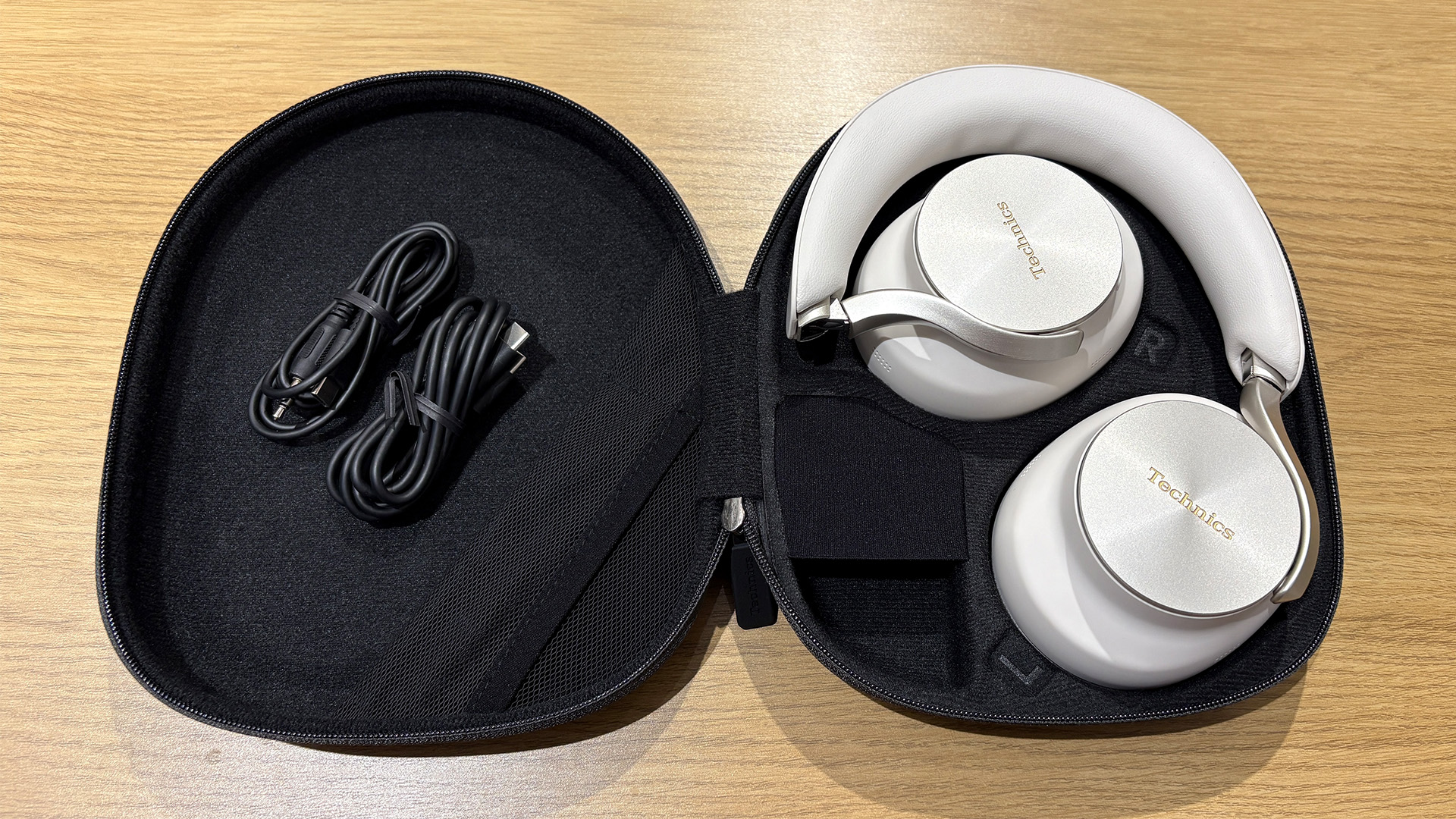 Technics EAH-A1000 wireless over-ear headphones in case on wooden surface