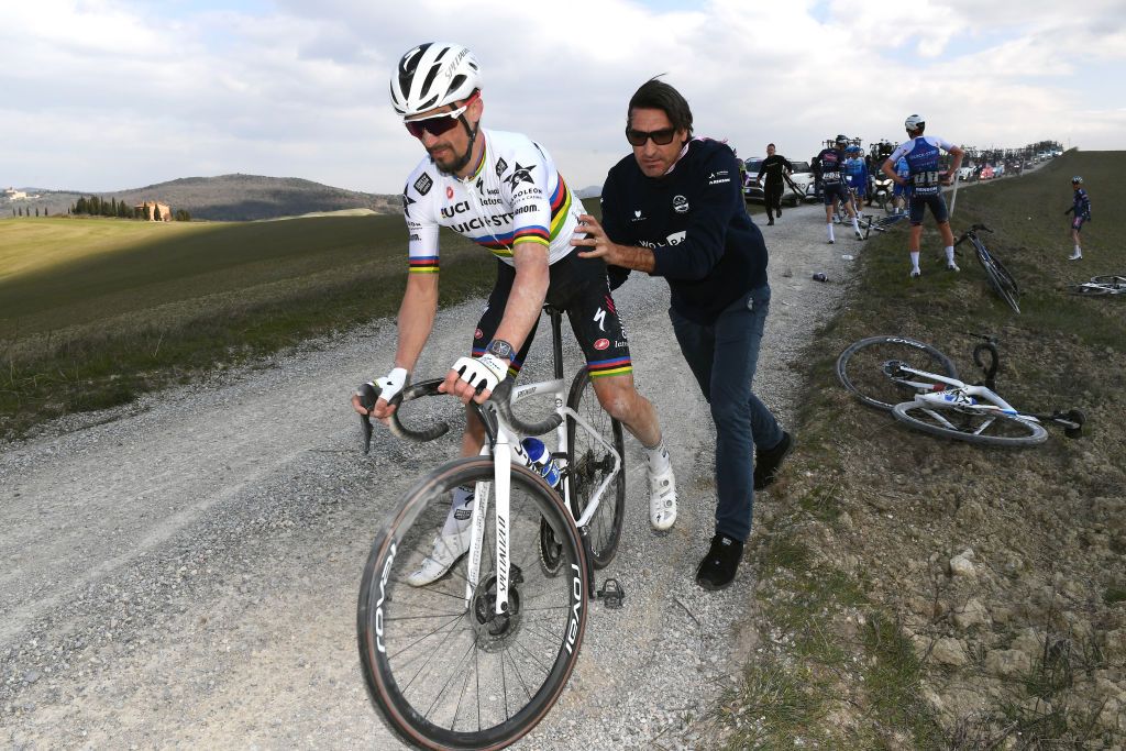 SIENA ITALY MARCH 05 Julian Alaphilippe of France and Team QuickStep Alpha Vinyl help by Davide Bramati Sports Director after being involved in a crash during the Eroica 16th Strade Bianche 2022 Mens Elite a 184km one day race from Siena to Siena Piazza del Campo 321m StradeBianche WorldTour on March 05 2022 in Siena Italy Photo by Tim de WaeleGetty Images