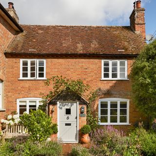 exterior of a red brick victorian cottage with sage green front door