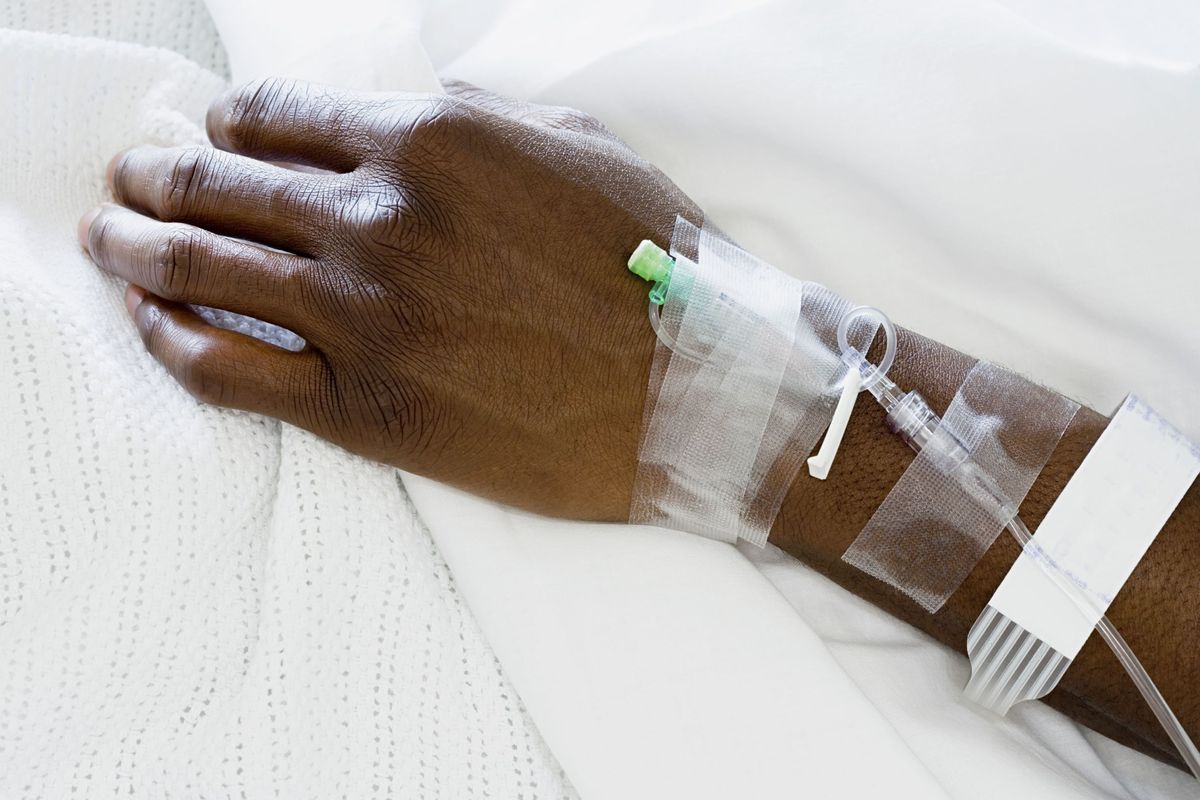 Close up of patient&#039;s arm with IV in hospital bed.