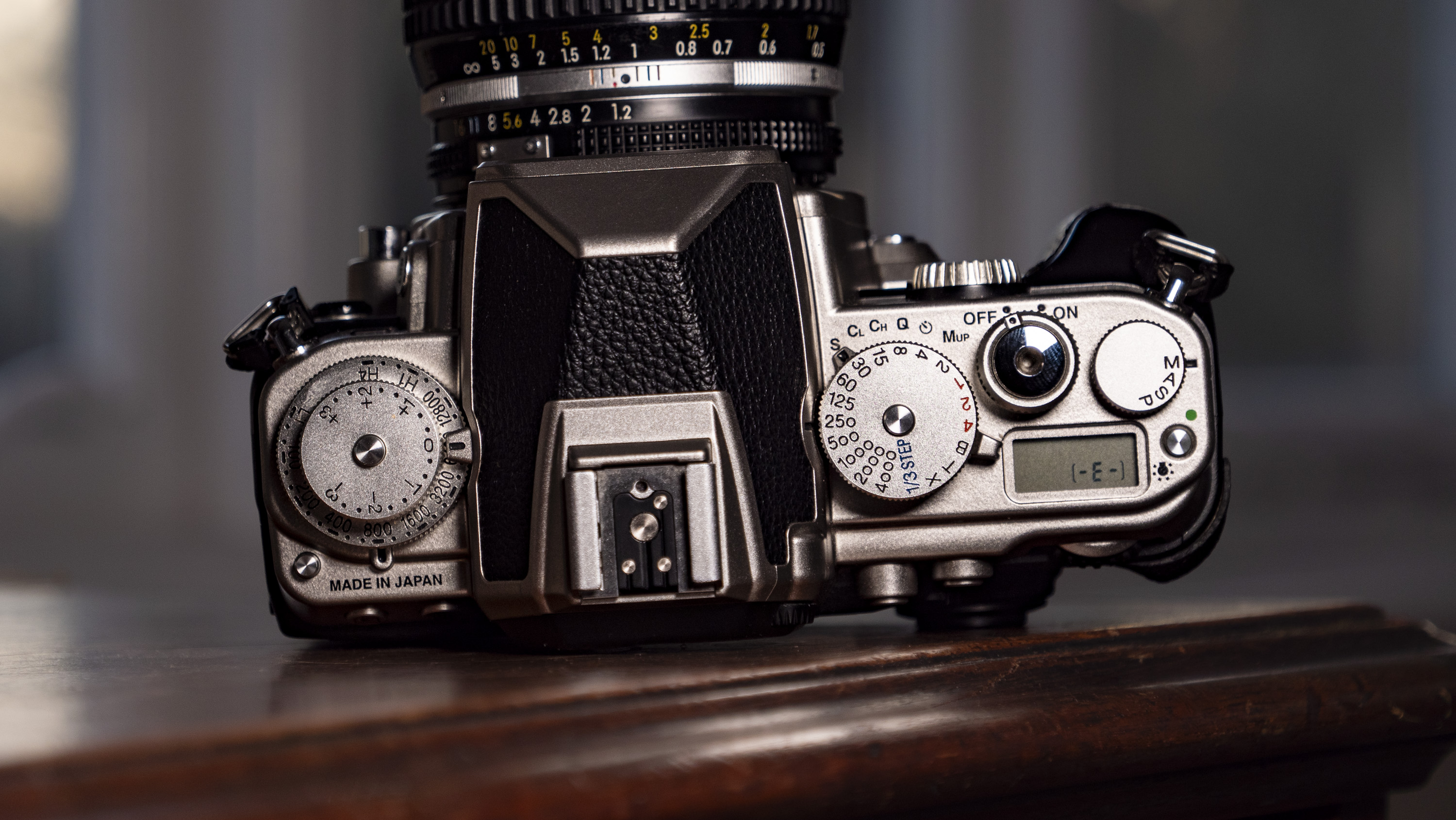 Nikon Df DSLR camera on a wooden surface by large window, with dusk light