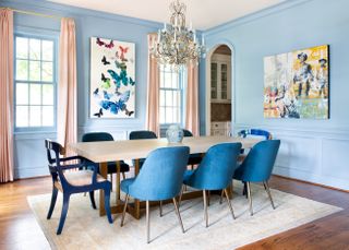 A dining room with blue walls and upholstered furniture