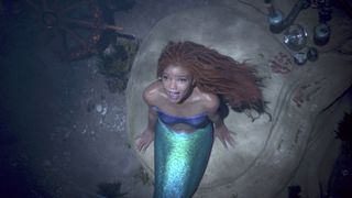 Ariel se sienta en una roca en el océano mientras canta en La Sirenita