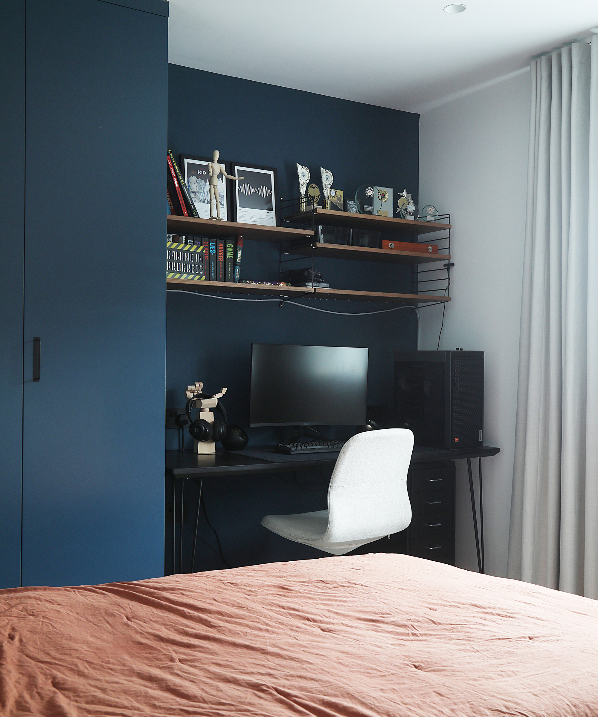 A navy blue bedroom with desk nook and navy blue cupboard